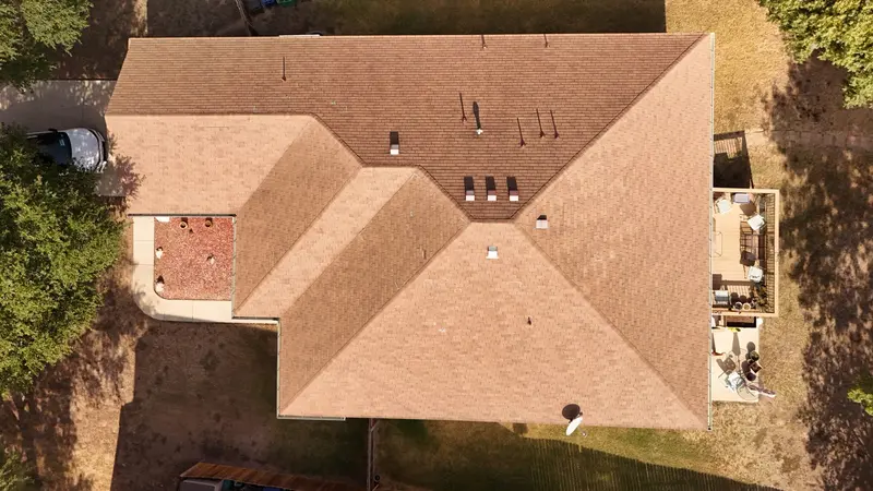 Aerial view of brick residential home with multi-level asphalt shingle roof and multiple roof valleys