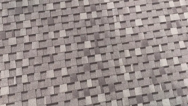Architectural asphalt shingles in gray and tan tones with staggered pattern and shadow depth