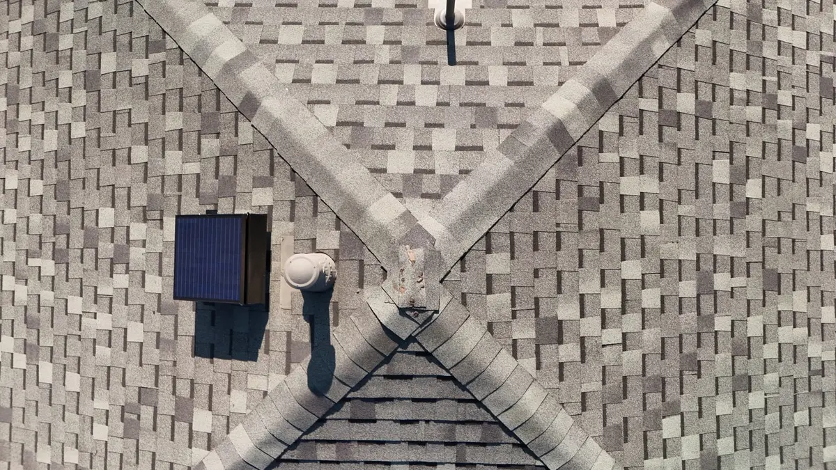 Aerial view of architectural shingle roof with herringbone pattern, solar panel, and metal flashing details