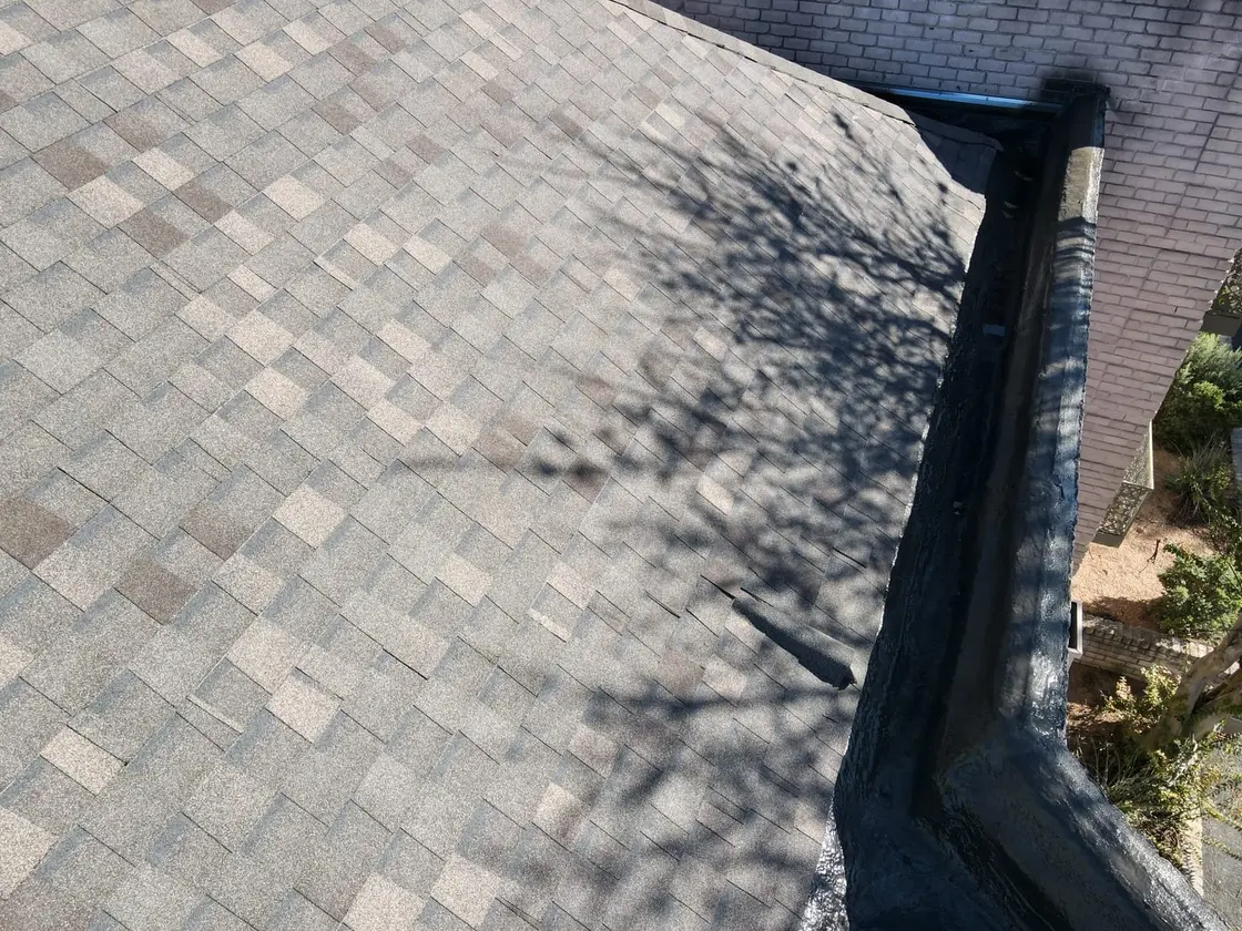 Gray K-style gutter running along the edge of an asphalt shingle roof