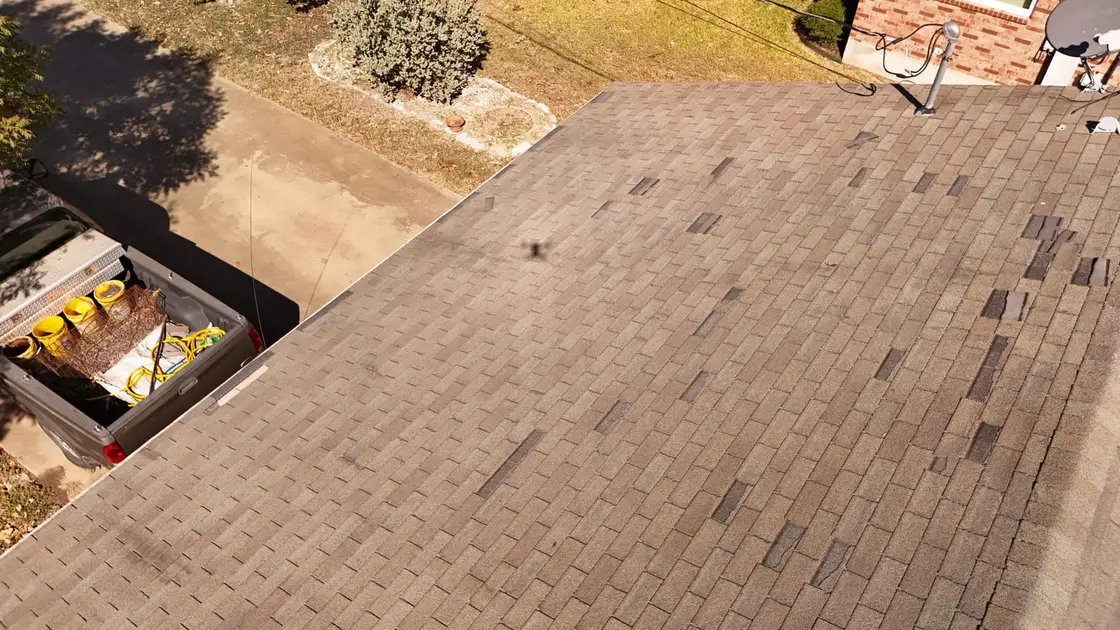 A roofer photographing hail damage on a shingle roof during a storm inspection