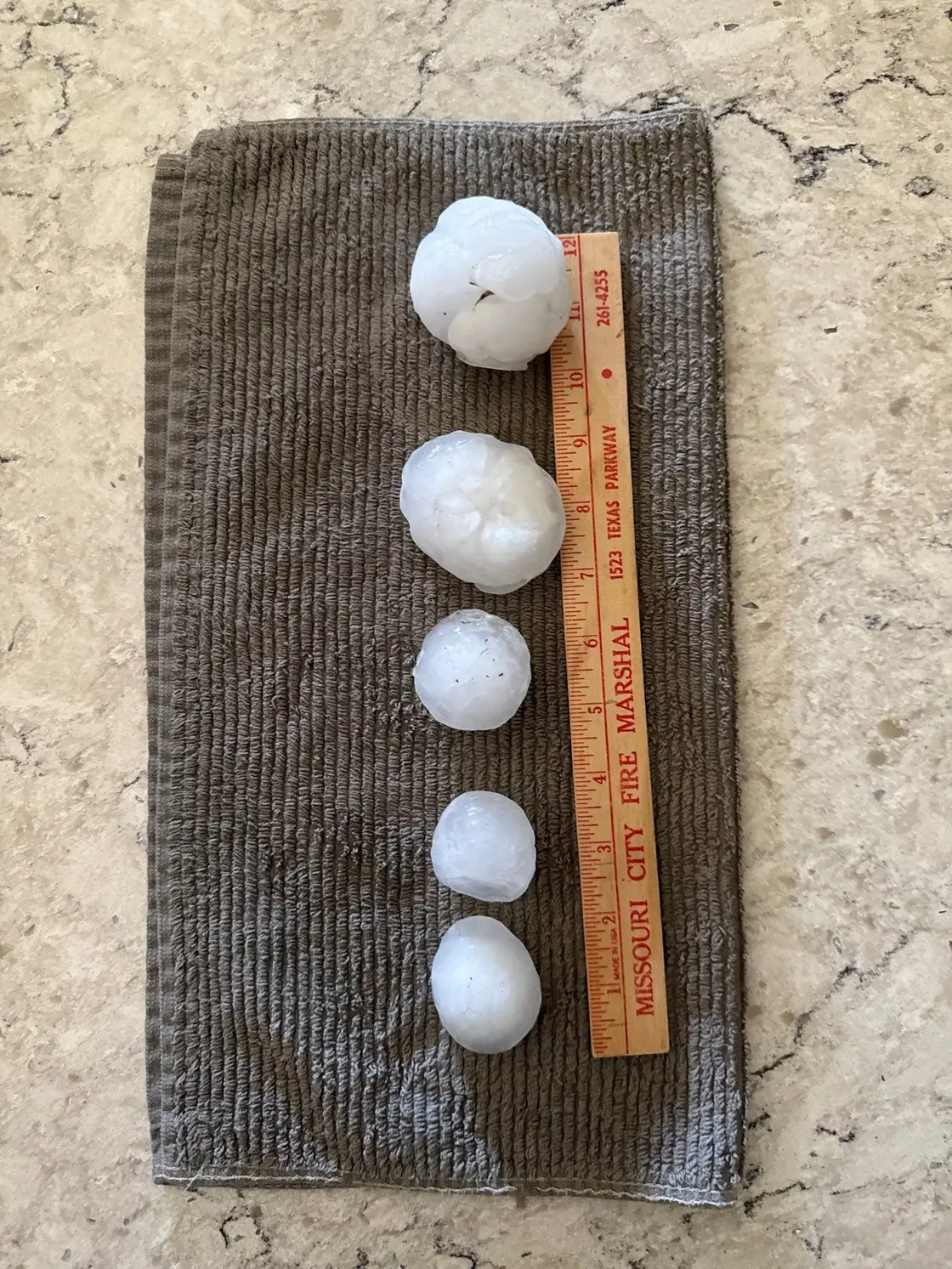 Hailstones sized against a coin to document storm severity for a roof claim
