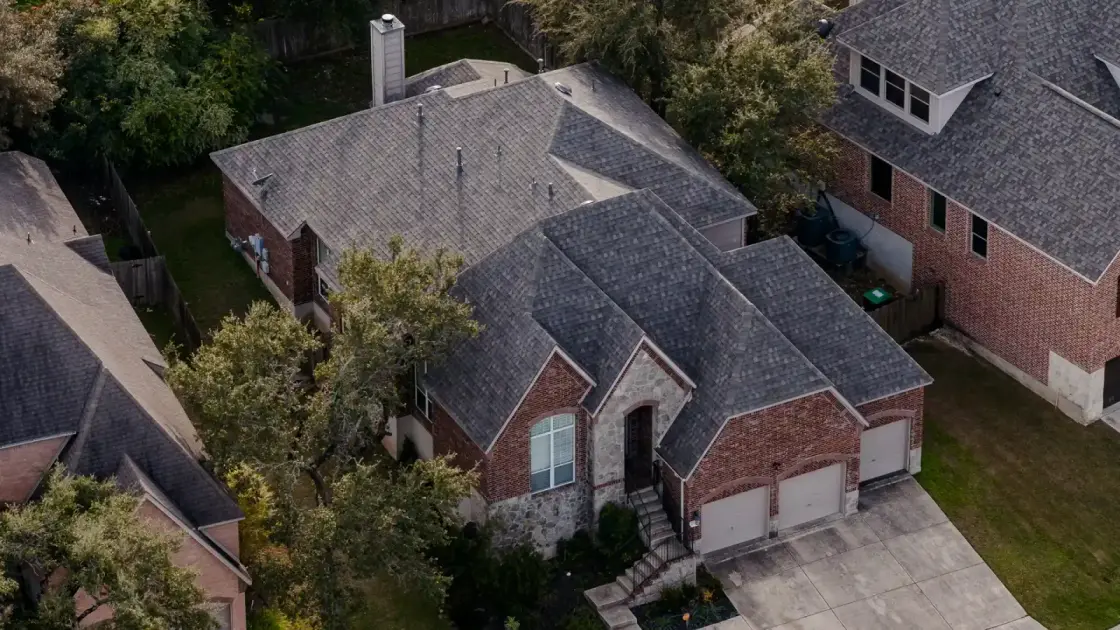 Aerial view of a gray asphalt shingle roof on a Texas brick home