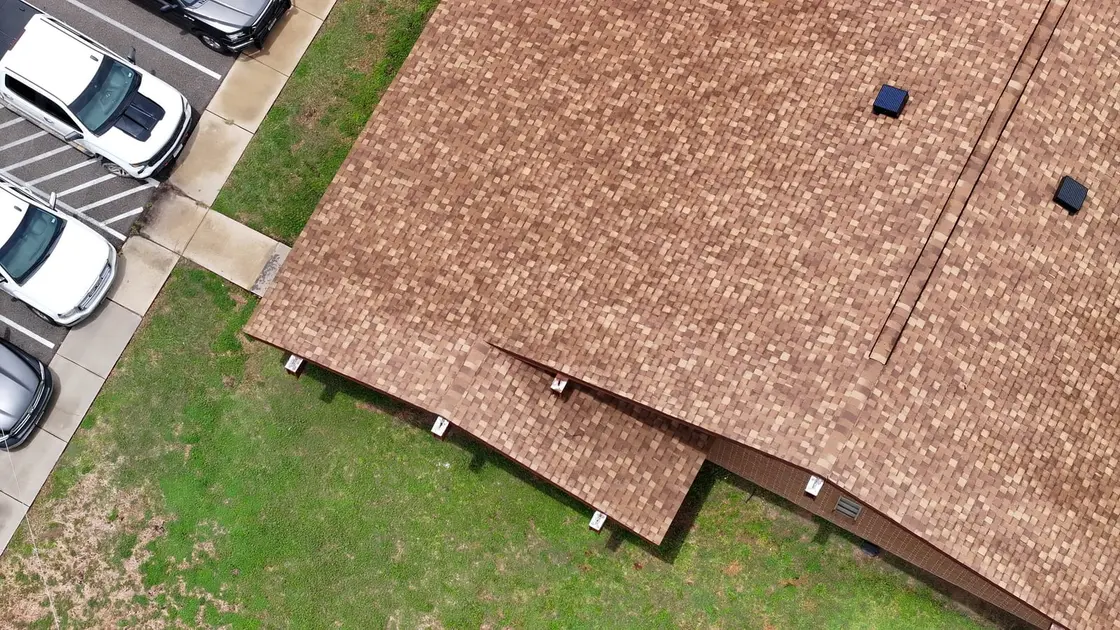 Aerial view of a Texas home's gutters running the roof edge under heavy tree cover