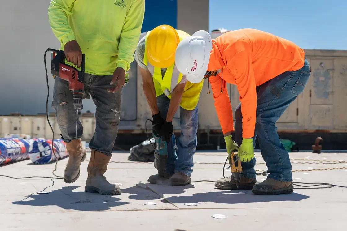 ARP crew drilling anchor points to mechanically fasten insulation board on a Texas commercial roof