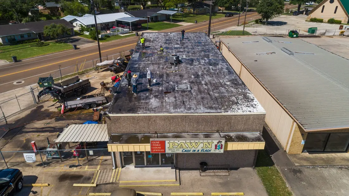 Old commercial roof being demolished and hauled off the deck during a full tear-off in Texas