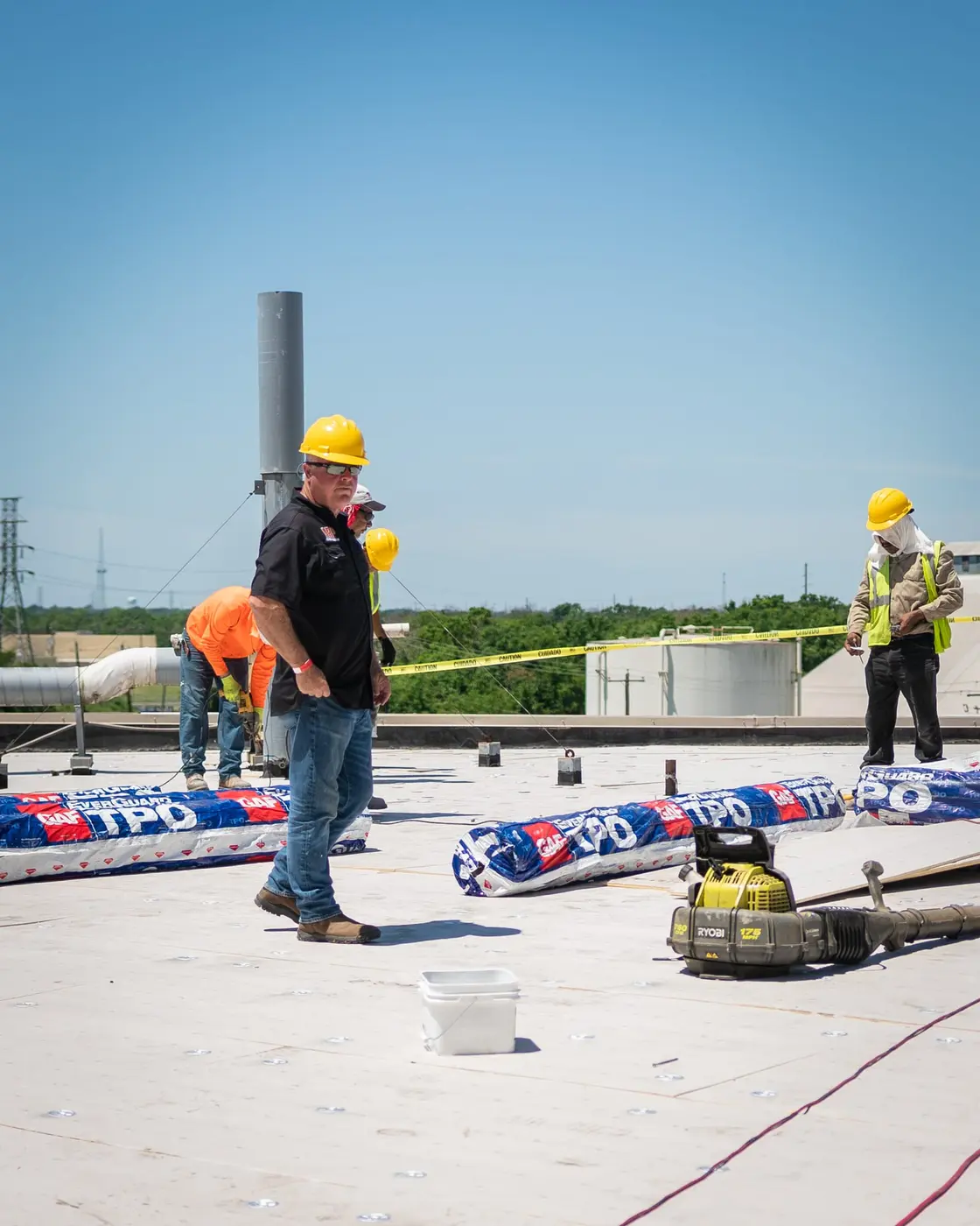 Roofing crew rolling out a modified bitumen sheet across a low-slope commercial deck in Texas