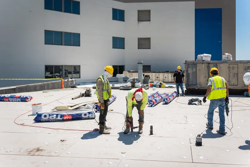 An ARP-supervised crew rebuilding a failed flat-roof section — the repair welded back into the sound membrane so the warranty holds.