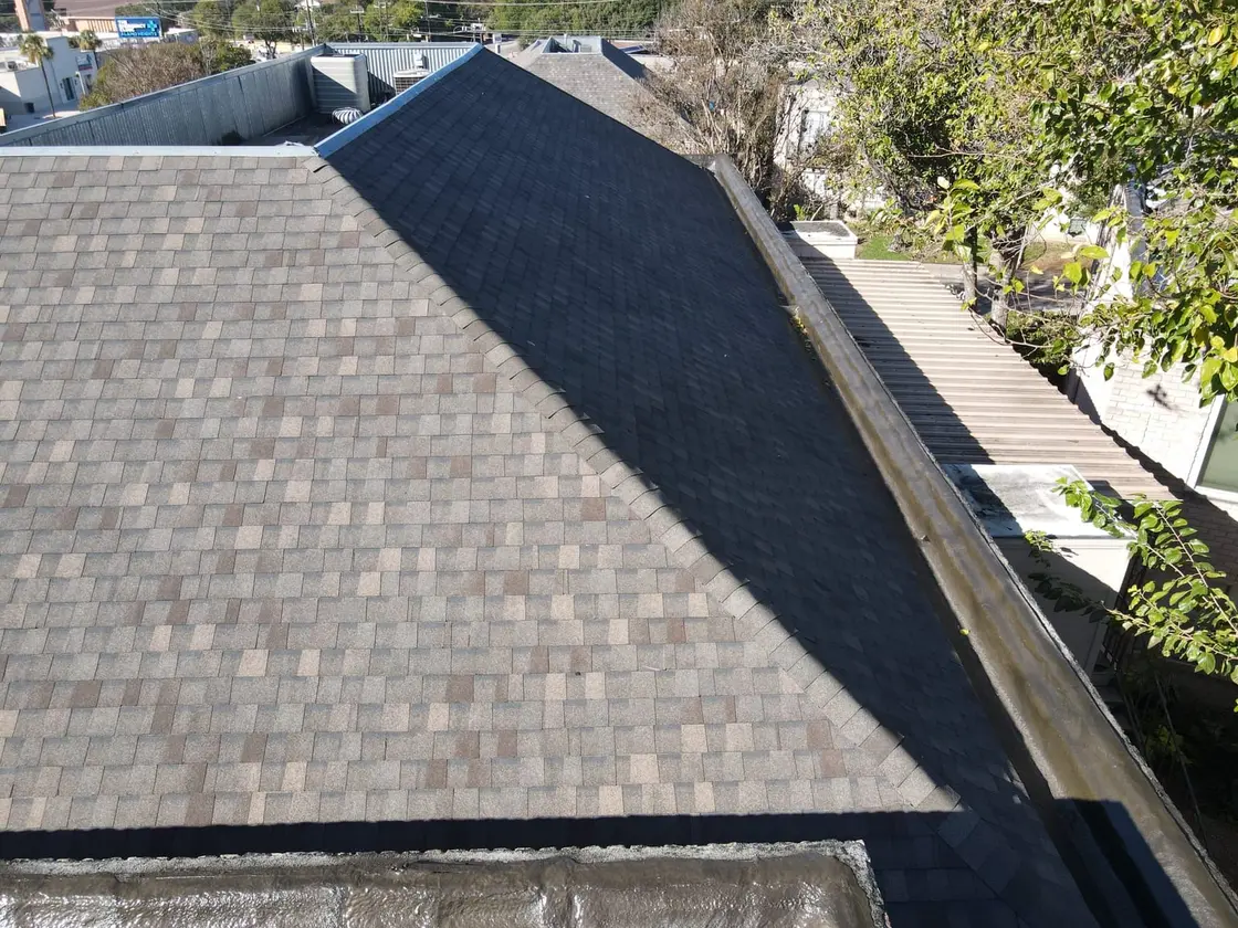 Gutter and downspout detail where a peaked commercial roof section ties into the drainage edge in Texas