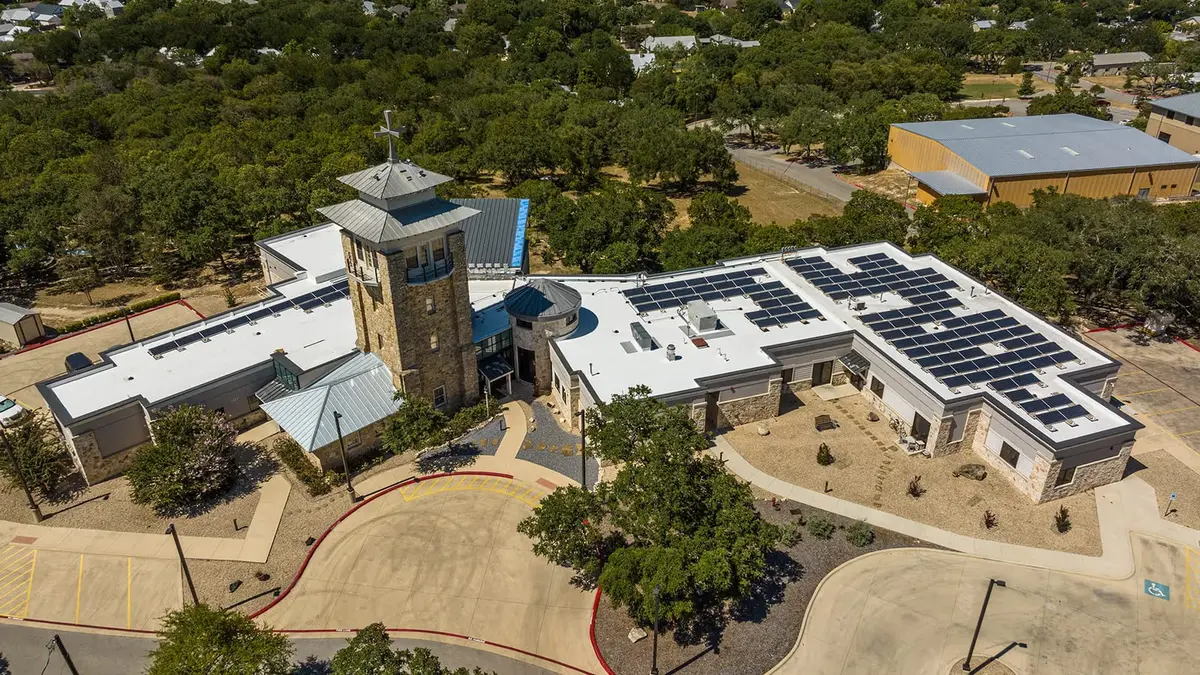 Aerial view of commercial buildings with white flat roofs and extensive solar panel arrays installed on multiple roof