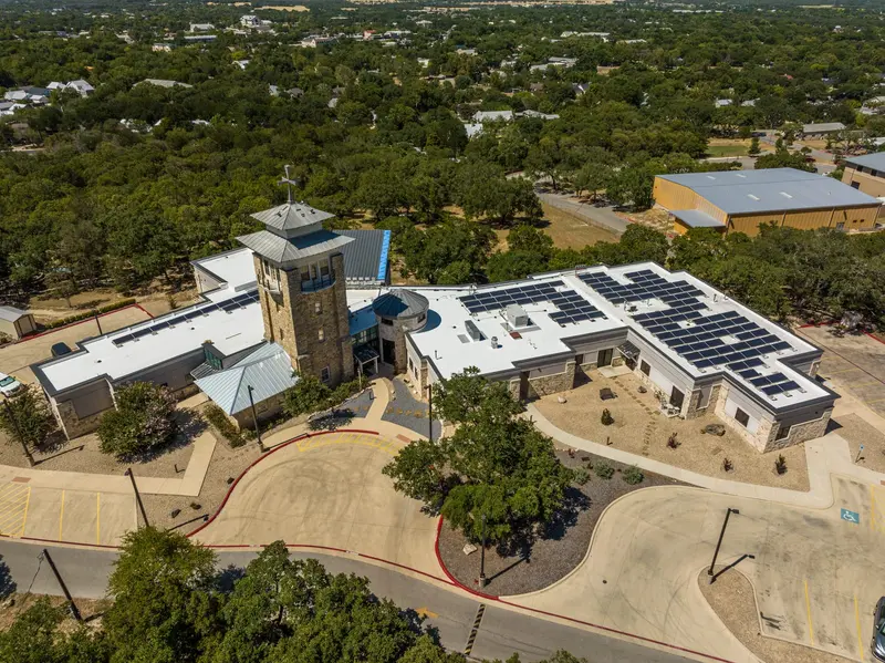 A reflective white TPO roof carrying rooftop solar — the low-slope surface that throws off the South Texas heat and gives the equipment a sound, watertight base.