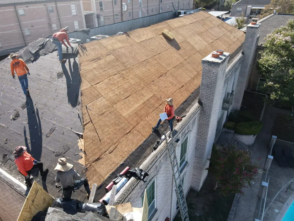 Roofing crew tearing off an old membrane on a commercial flat roof before a single-ply replacement
