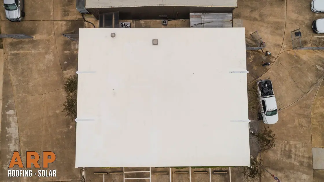 Overhead view of a white single-ply membrane flat roof, its seams and edge terminations visible