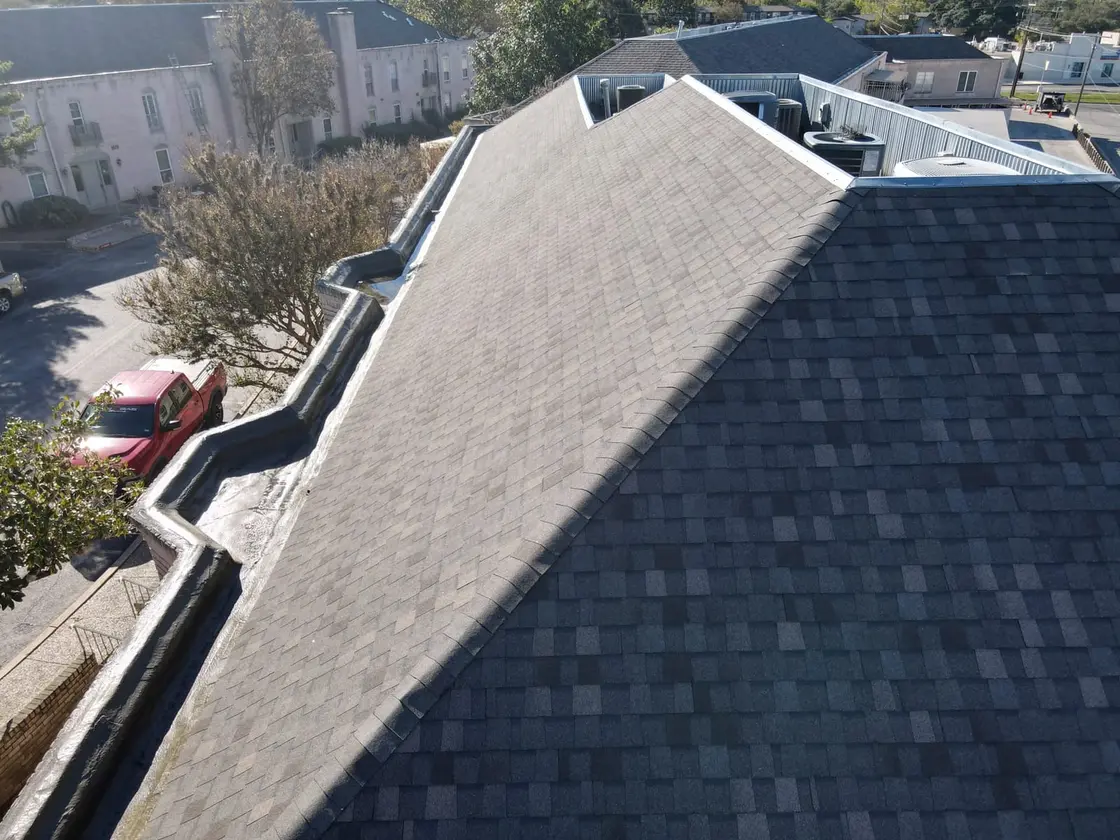 Aerial of a commercial low-slope roof in Texas with box gutters and downspouts carrying runoff to grade