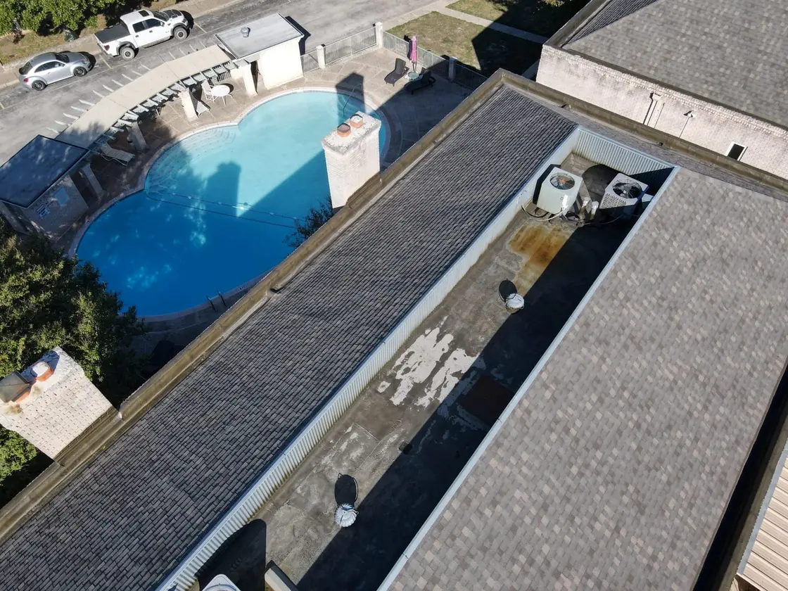 Aerial view of a low-slope commercial roof with rooftop HVAC units and a reflective single-ply membrane on a Texas building