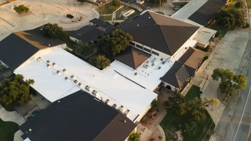 A low-slope commercial roof read from the air — on a repair, we trace the leak to its source before we quote the fix.