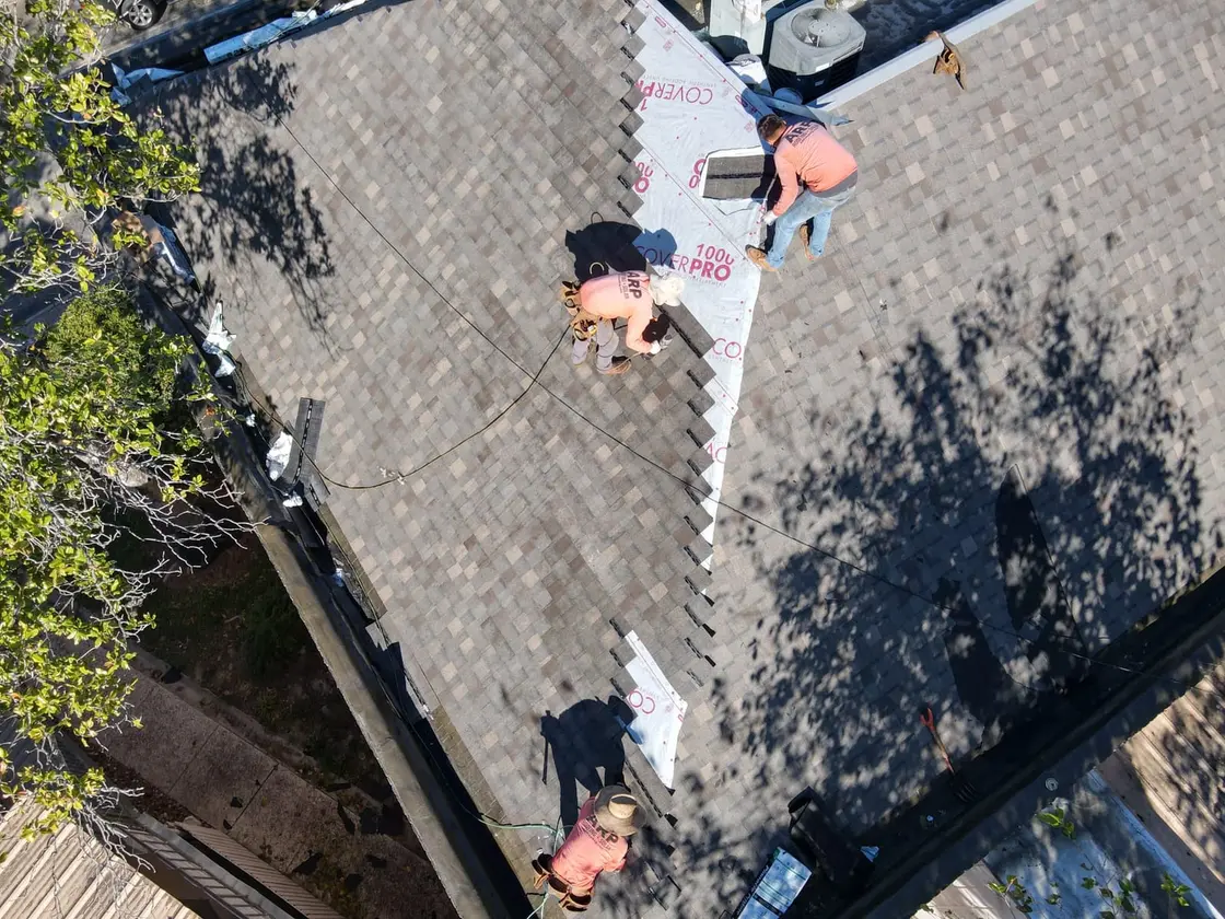 ARP-supervised crew rolling out and heat-welding a white TPO single-ply membrane across a flat commercial roof deck in Texas
