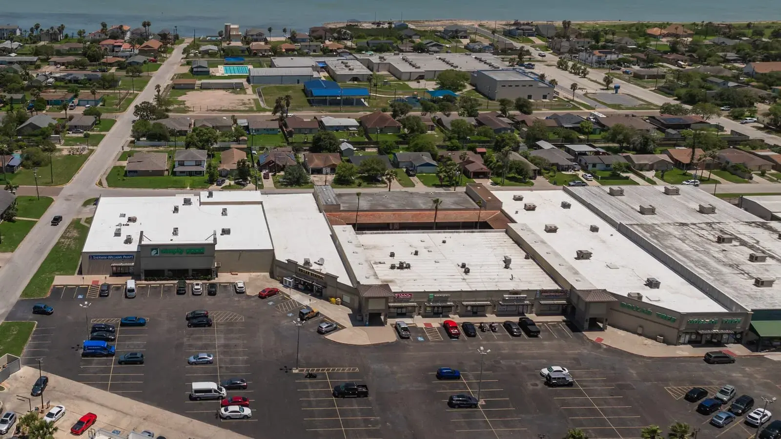Aerial view of a shopping center whose flat roofs carry a white reflective restoration coating