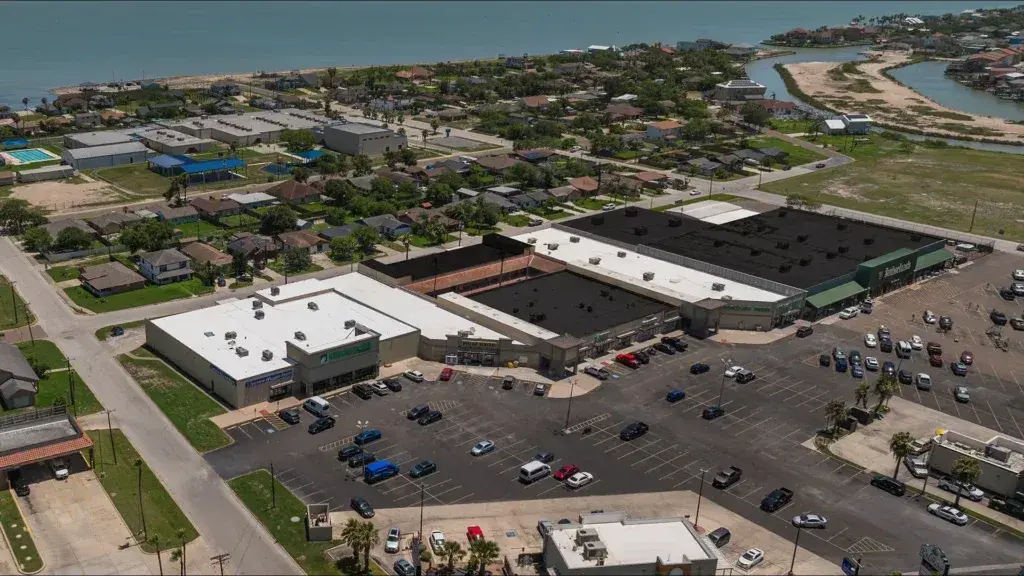 Aerial of a broad white TPO warehouse roof in Texas where slope has to move water across the whole field