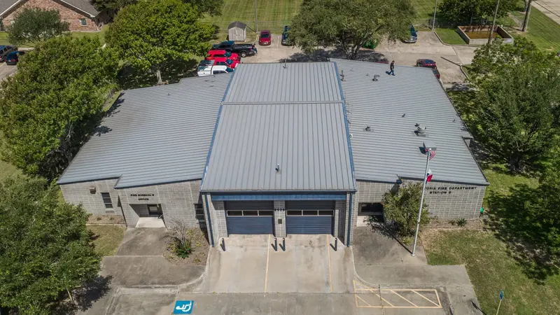 The Victoria Fire Station — its old, rusting standing-seam roof restored with a gray coating instead of a tear-off, applied over the occupied building without shutting it down.