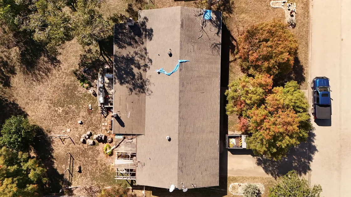 Aerial view of a low-slope roof with a tarp covering a failed section after water got in