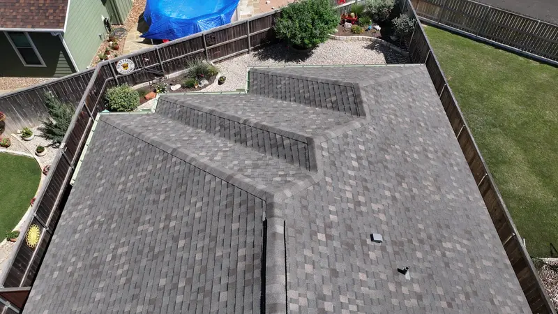 Aerial view of new gray architectural asphalt shingle roof installation on residential home with multiple roof planes and