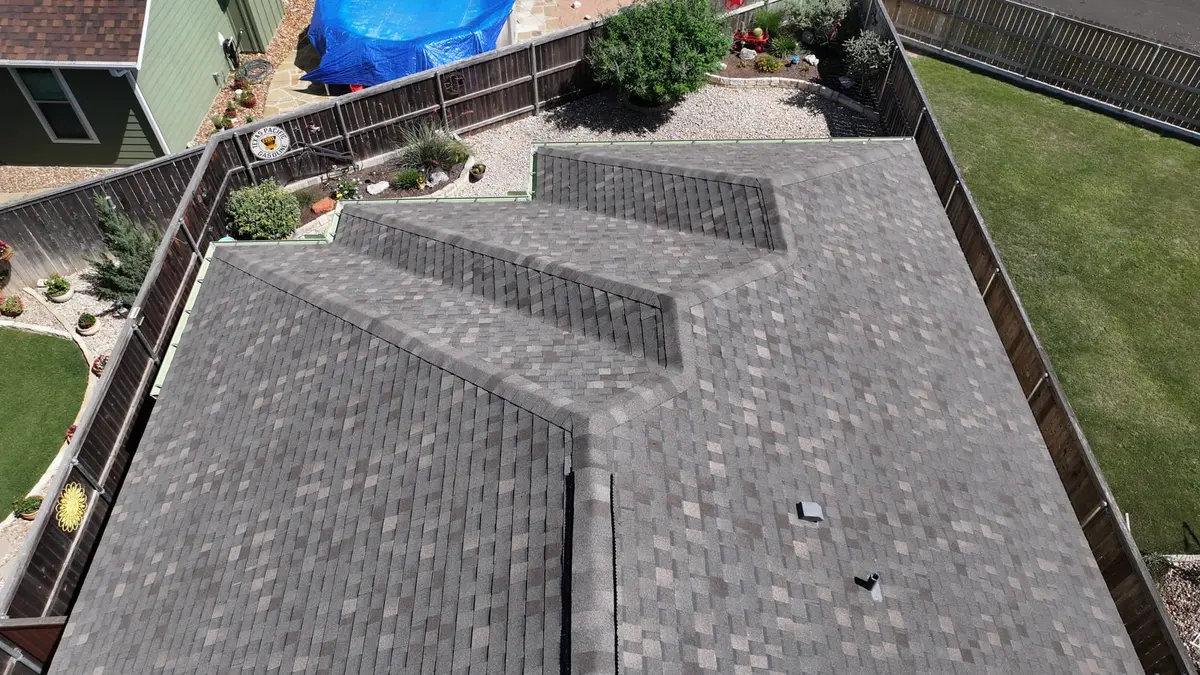 Aerial view of new gray architectural asphalt shingle roof installation on residential home with multiple roof planes and