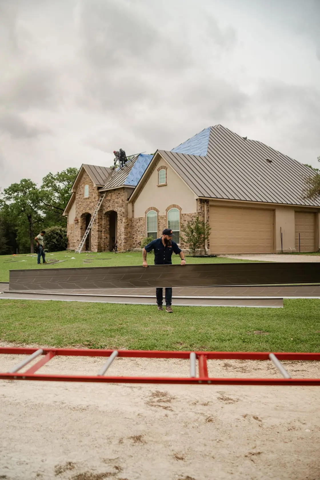 A crew installing standing seam metal panels on a residential roof in Texas