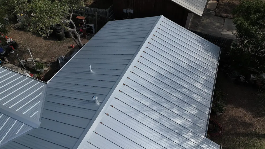 Aerial view of a residential metal standing seam roof with multiple planes and fasteners visible
