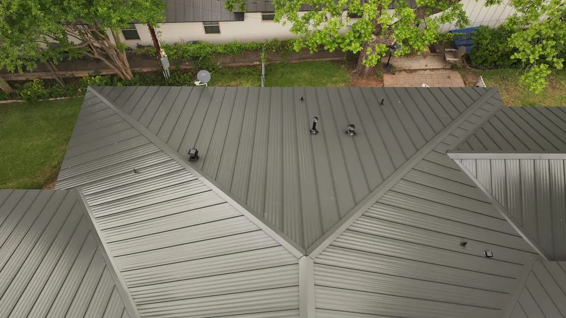 Crew installing mechanical double-lock standing seam panels on a residential roof