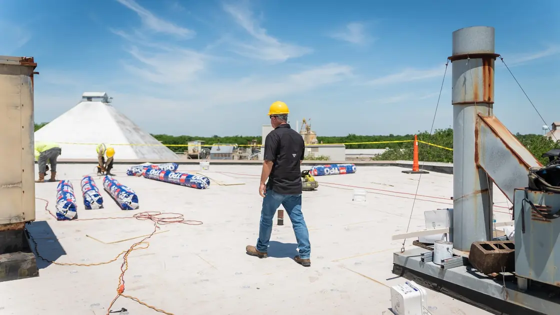 Roofing crew building a low-slope asphalt membrane on a commercial deck in Texas