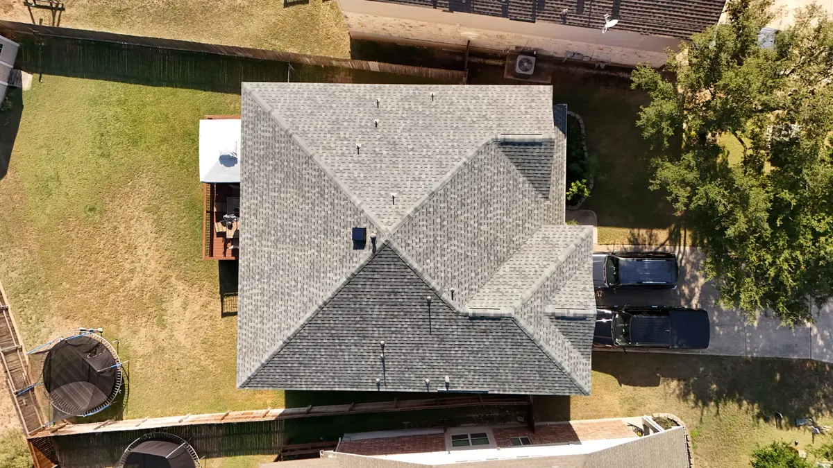 Aerial view of residential home with new gray architectural asphalt shingle roof, complex multi-peak design, driveway with