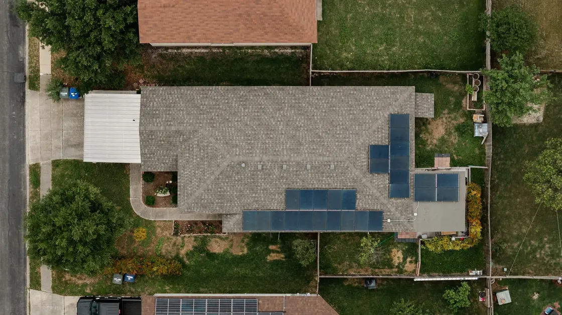 Aerial view of a residential asphalt shingle roof covered by a solar panel array