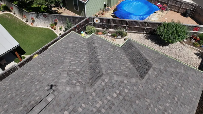 Aerial view of residential two-story home with gray architectural asphalt shingle roof featuring dual peaks and valleys
