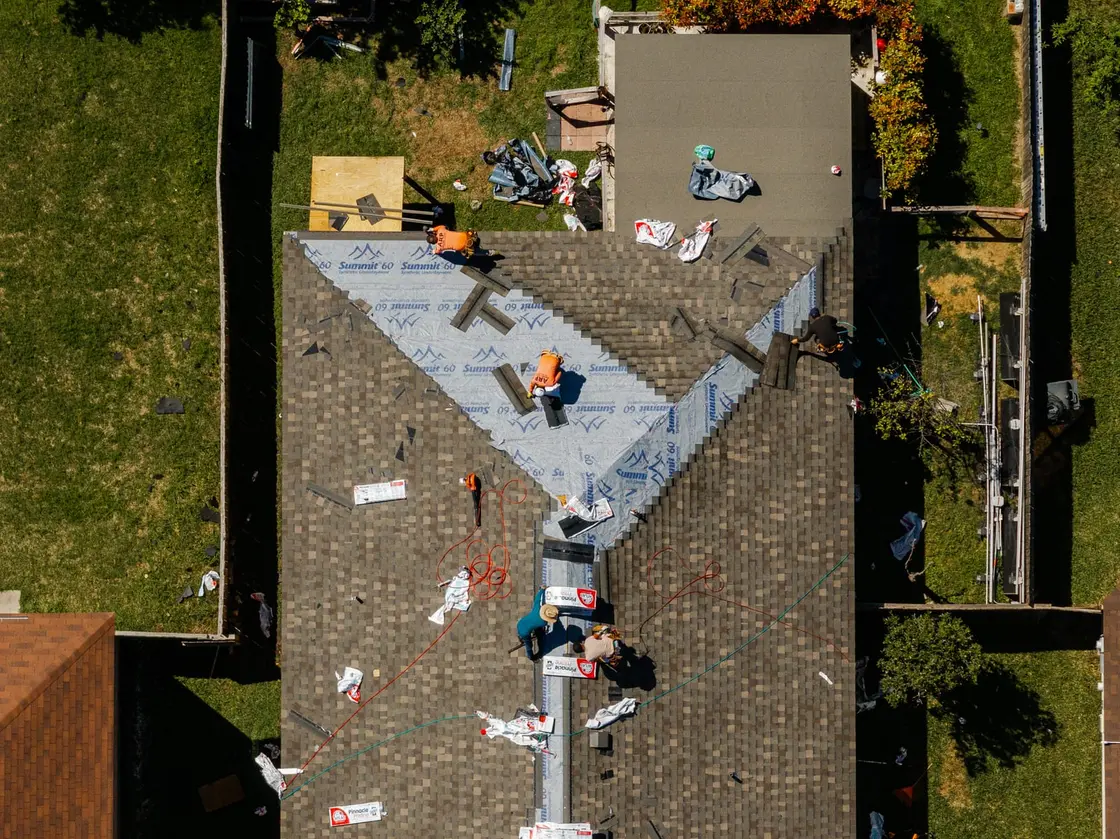 Roofing crew installing asphalt shingles during a residential roof replacement