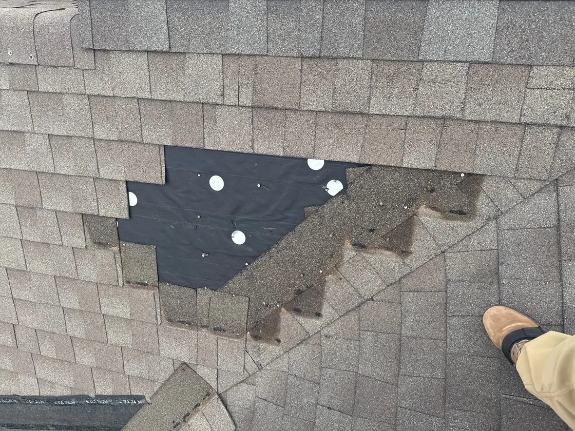 Asphalt shingles torn off a Texas roof after a windstorm, exposing bare underlayment
