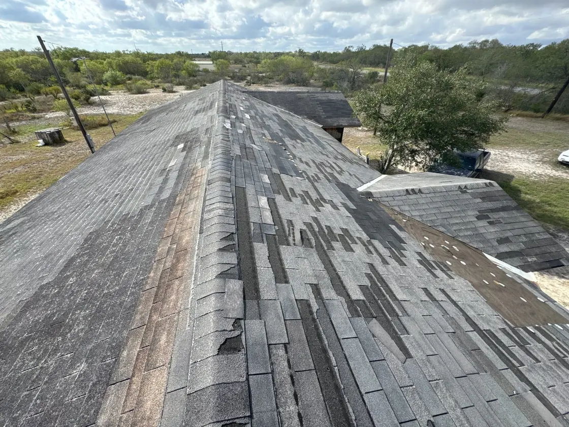 Whole slopes of a Texas roof stripped of shingles by the row after a windstorm